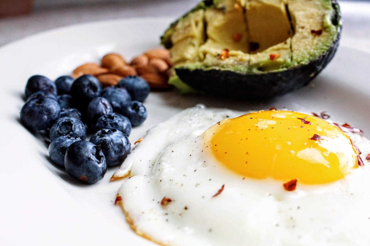 home-img A nutritious breakfast featuring a fried egg, avocado, blueberries, and almonds.