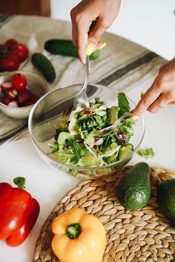 our-story Hands preparing a fresh vegetable salad with cucumbers, peppers, and lettuce in a kitchen setting.